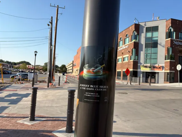 Johnny Blue Skies ashtray poster on a black pole at Mill Street, Westport, the Signal Theory building and a corner storefront