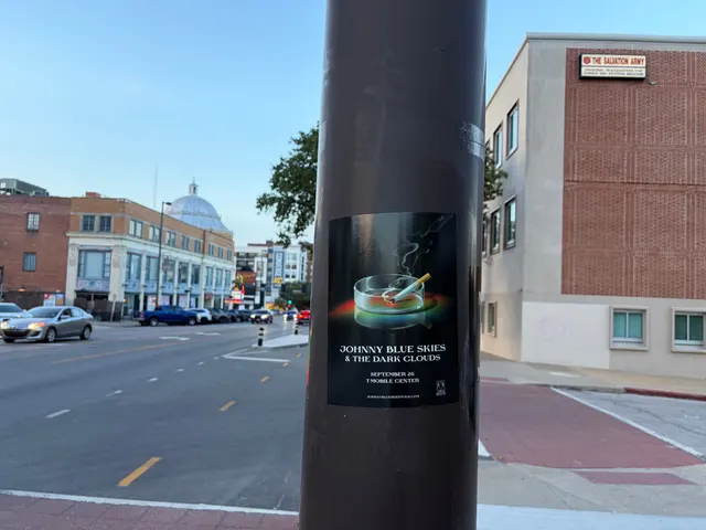 Johnny Blue Skies ashtray poster on a dark pole at Broadway Boulevard, Hanover Place, the Salvation Army building at dusk