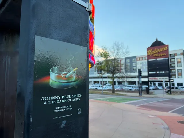 Johnny Blue Skies ashtray poster on a black pole at Broadway Boulevard, Hanover Place, the neon Uptown Theater marquee glowing at dusk