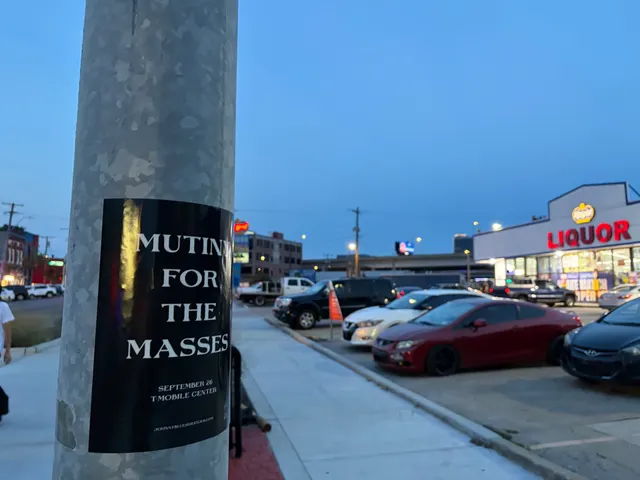 Mutiny for the Masses pole snipe on a galvanized pole at Southwest Boulevard, a lit Liquor store sign and a red coupe in the lot at dusk