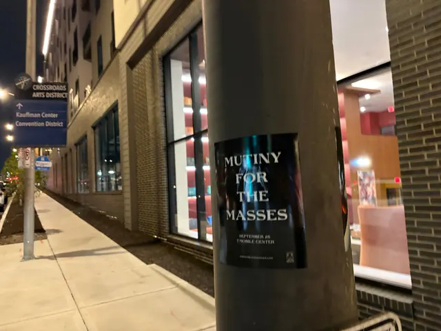 Mutiny for the Masses pole snipe at Southwest Boulevard, Crossroads, a wayfinding sign pointing toward Kauffman Center at night