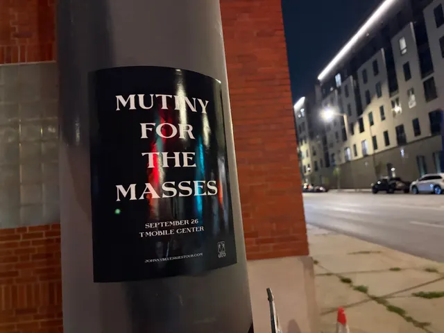 Mutiny for the Masses pole snipe on a metal pole at Southwest Boulevard, Crossroads, brick apartments under streetlights